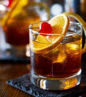 Old fashioned cocktail with orange and cherry